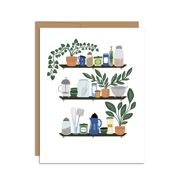 Single folded A2 greeting card with an envelope with an illustration of three shelves displaying various kitchen items such as a french press, mugs, and plants.