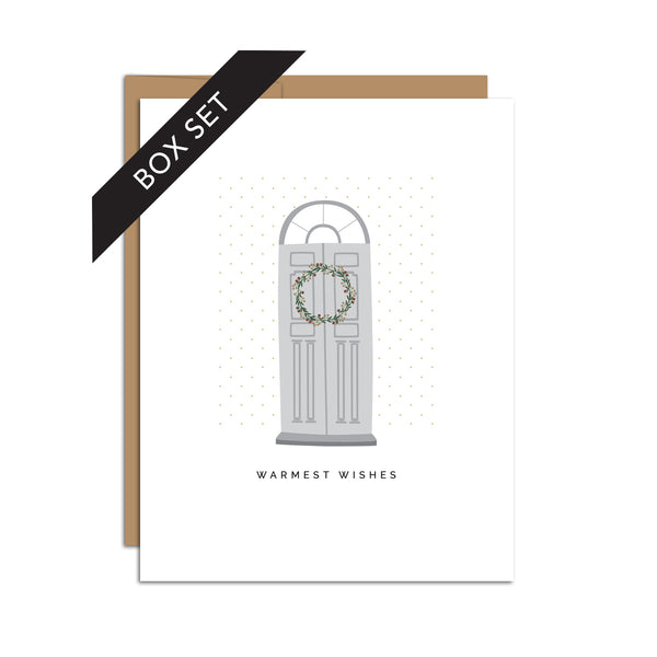 Box set of 8 folded A2 greeting cards with envelopes with an illustration  of a gray door with a wreath and directly below it is text that states "Warmest Wishes".