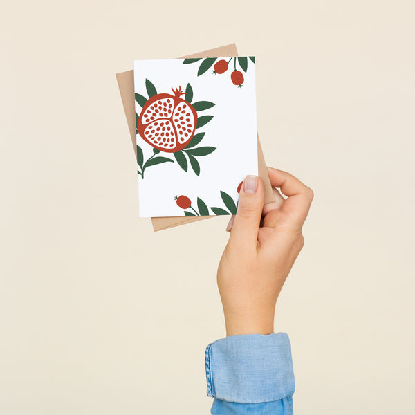Box set of 8 folded A2 greeting cards with envelopes with an illustration a pomegranate with seeds and green leaves.