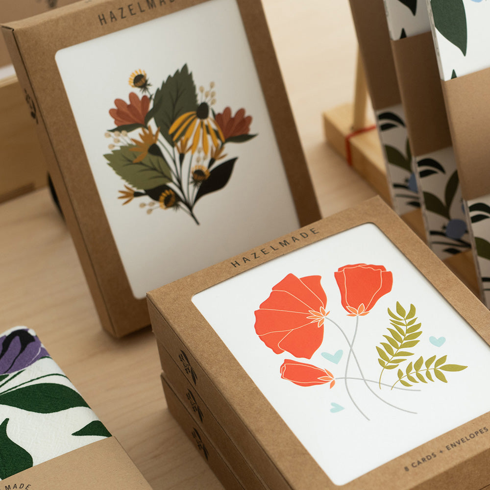 Hand-illustrated boxed greeting cards displayed on a table with Hazelmade packaging