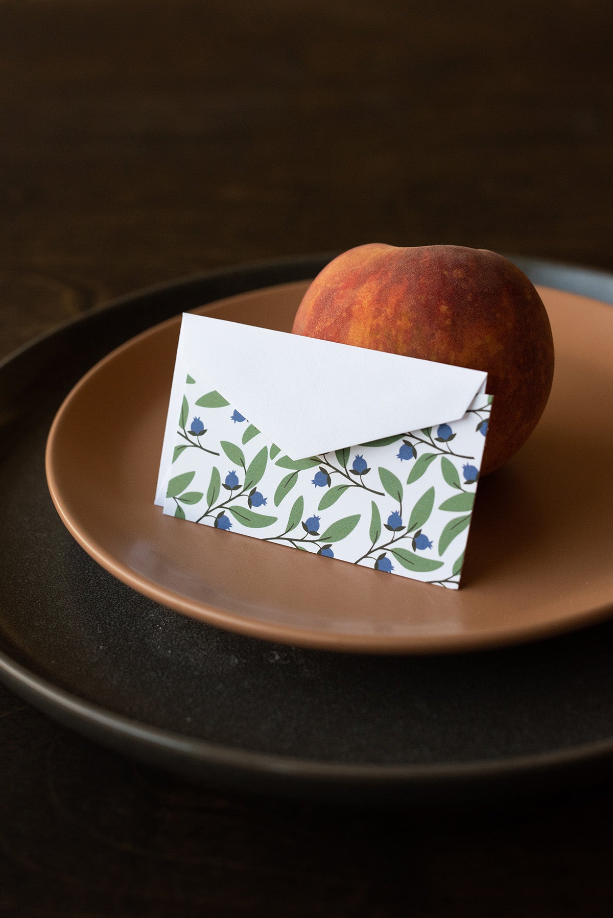 Hazelmade blueberry bushel mini note card and envelope styled with a peach on layered plates
