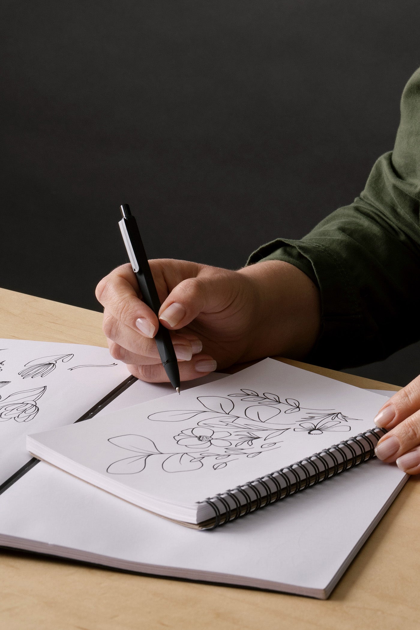 Susan Hazel Rich drawing one of her hand-illustrated designs in a sketchbook at her desk