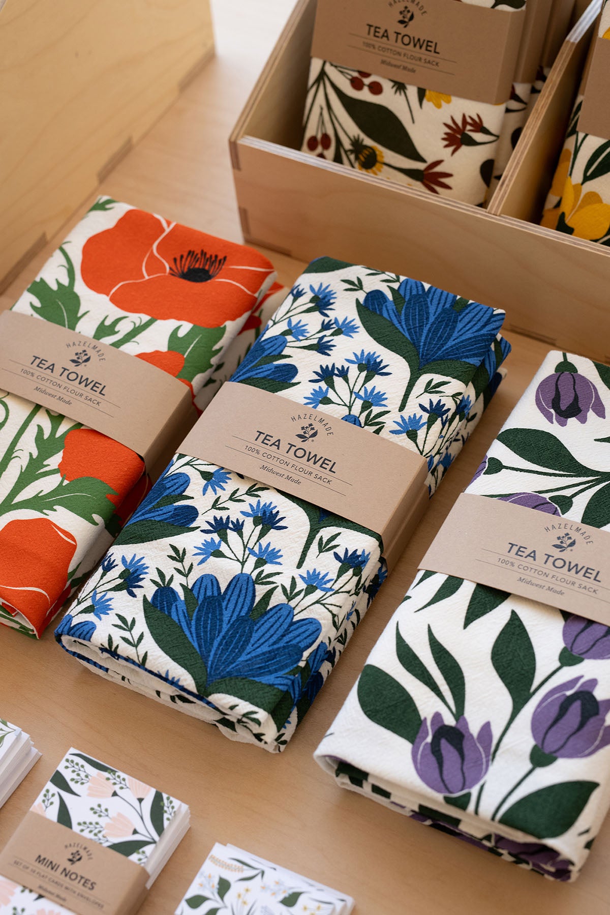 Assorted Hazelmade tea towels and mini note cards arranged on display