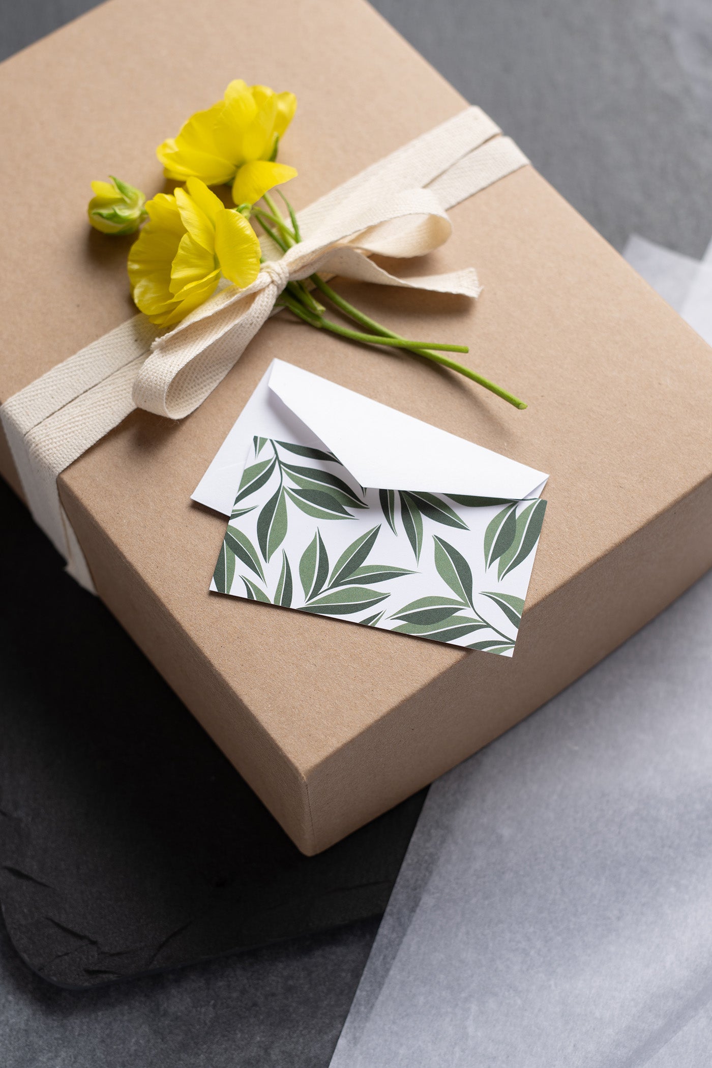 Hand-illustrated mini note card and envelope on a wrapped gift box with yellow flowers