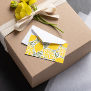 Lemons Mini Note Card and white envelope sitting on a wrapped gift box with ribbon and yellow flowers