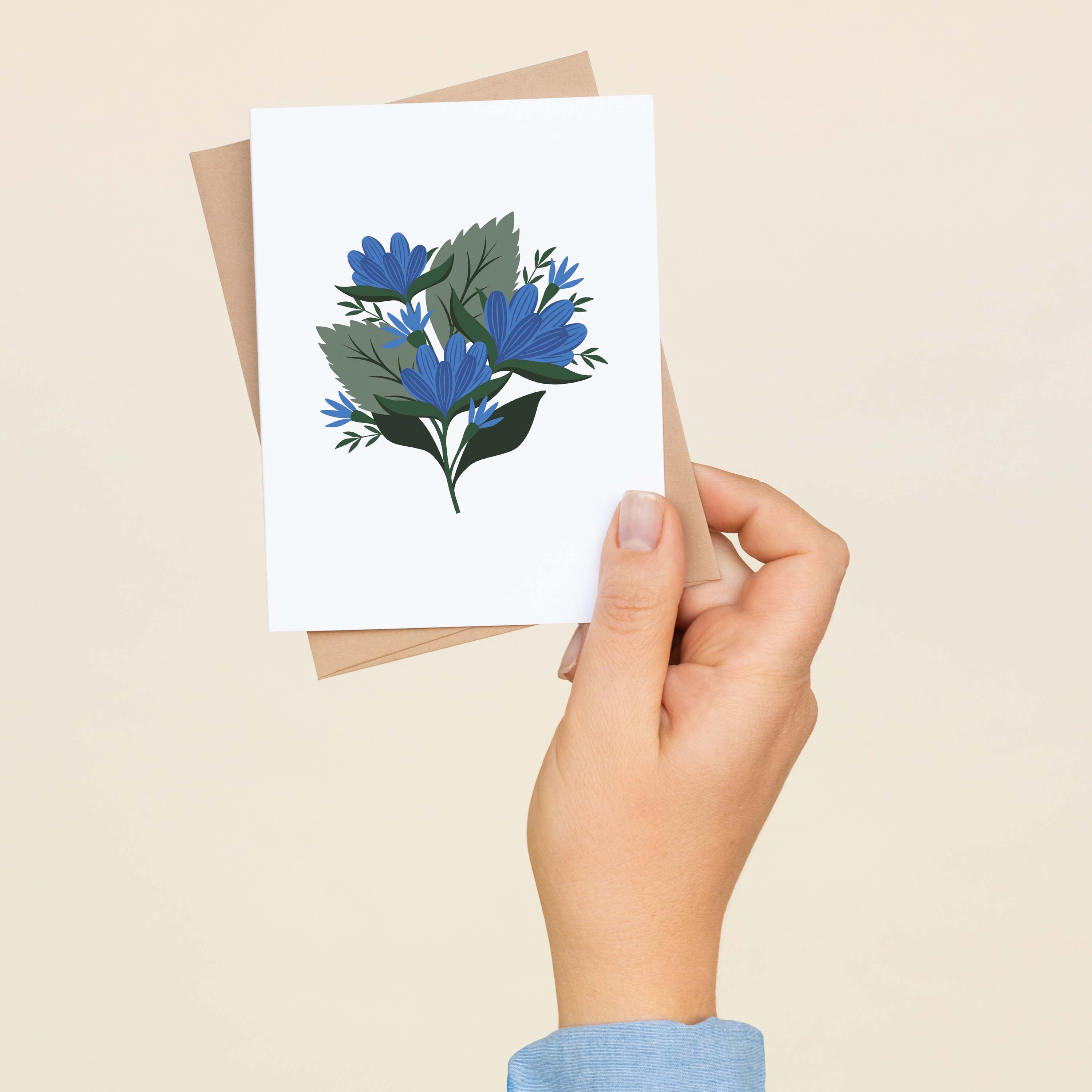 A hand holding a Blue Gentian greeting card showing the hand-illustrated blue gentian flower design