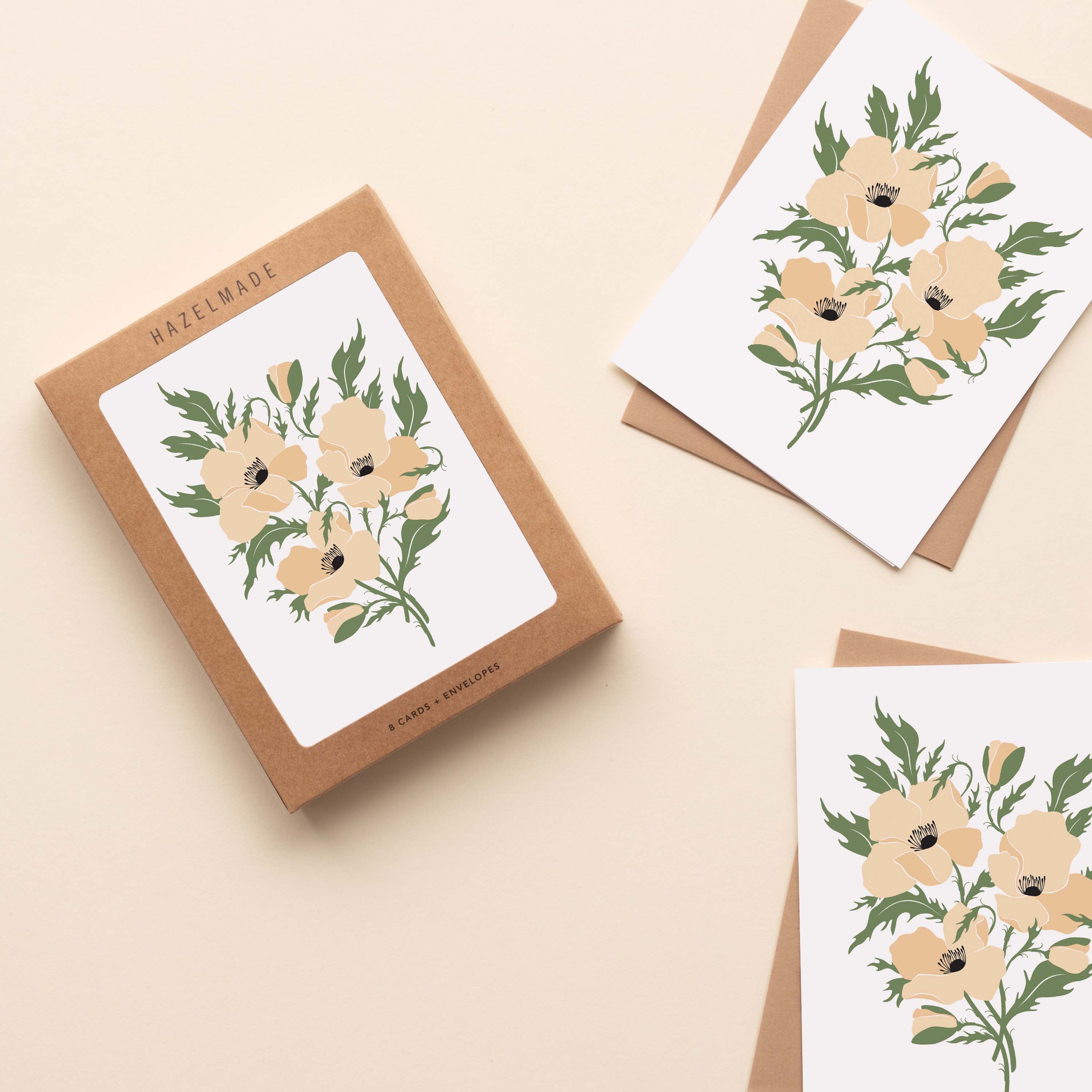A boxed set of White Windflowers Greeting Cards sitting with two cards and their envelopes featuring a hand-illustrated white windflower design