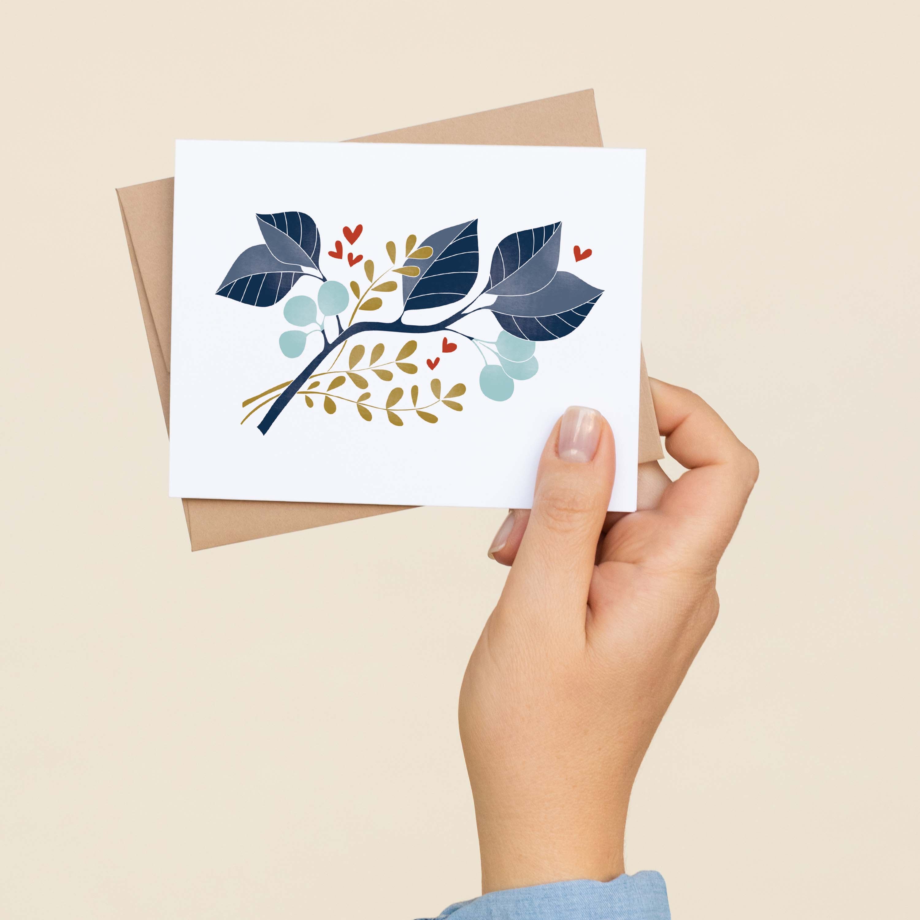 A hand holding a Magnolia Branch greeting card and envelope showing the hand-illustrated magnolia branch design