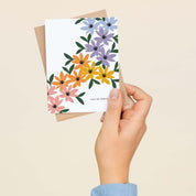 A hand holding the You're Perfect Rainbow Florals greeting card and envelope showing the hand-illustrated rainbow floral design