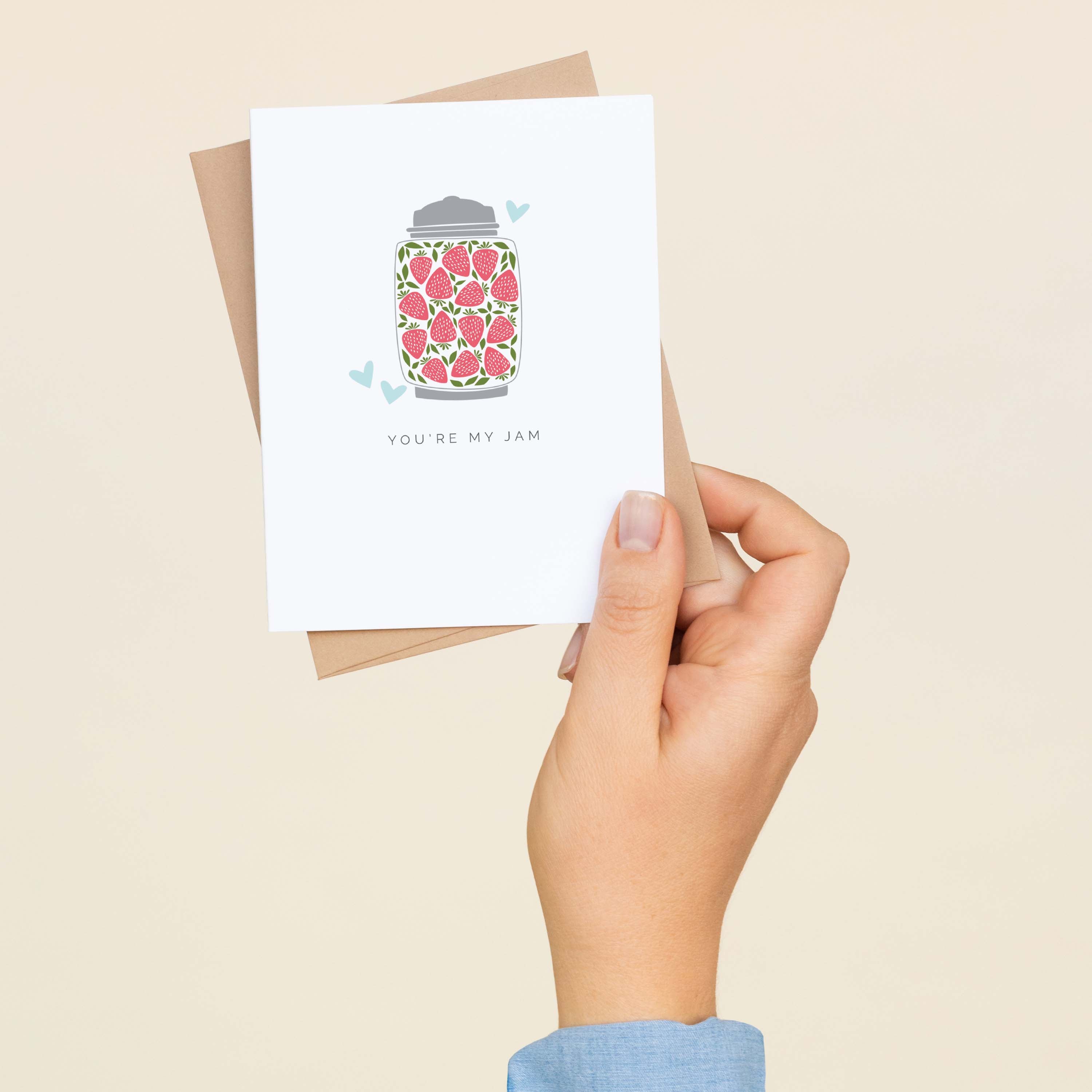 A hand holding the You're My Jam greeting card and envelope showing the hand-illustrated jar of jam design