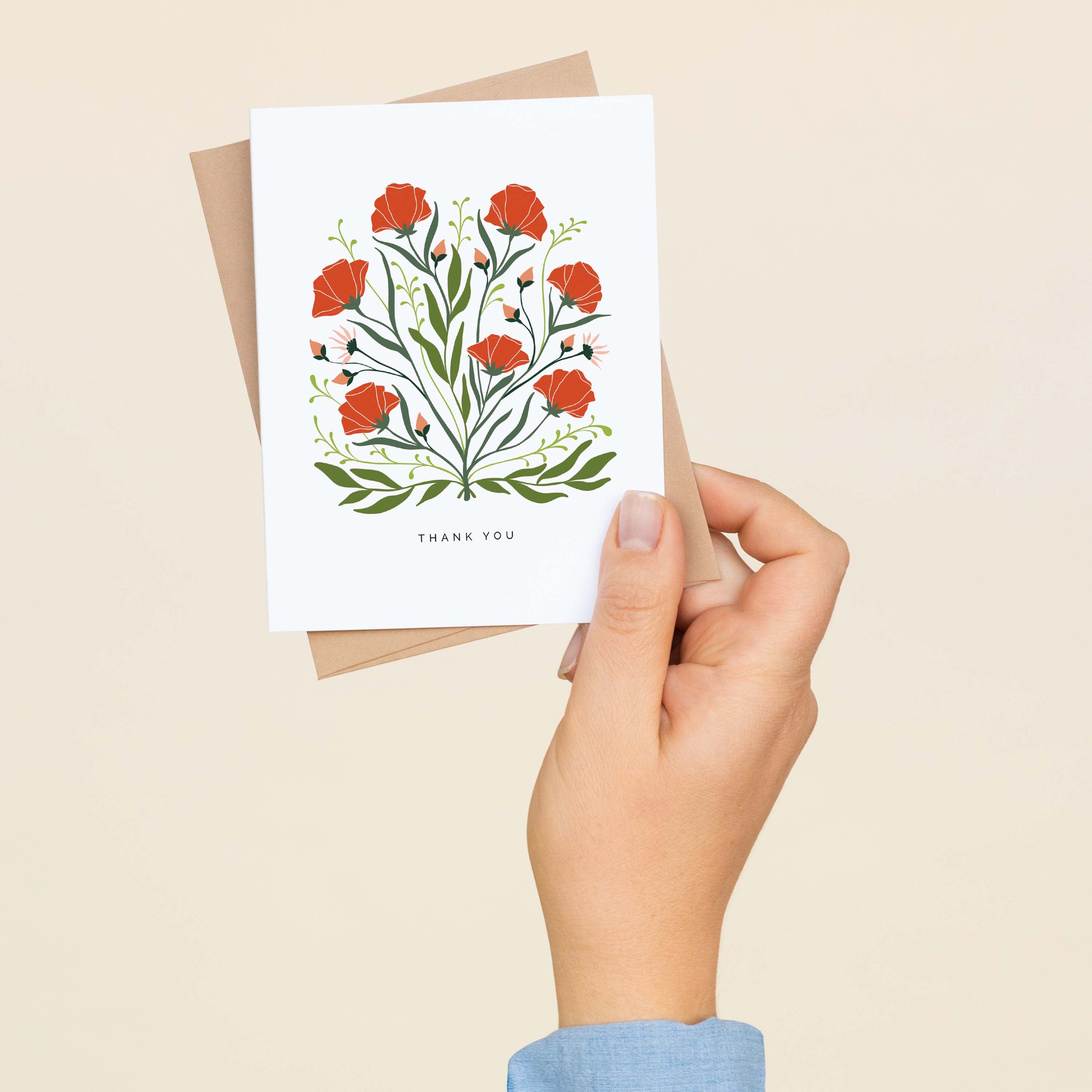 A hand holding a Poppies + Wildflowers Thank You greeting card and envelope showing the hand-illustrated poppies and wildflowers design