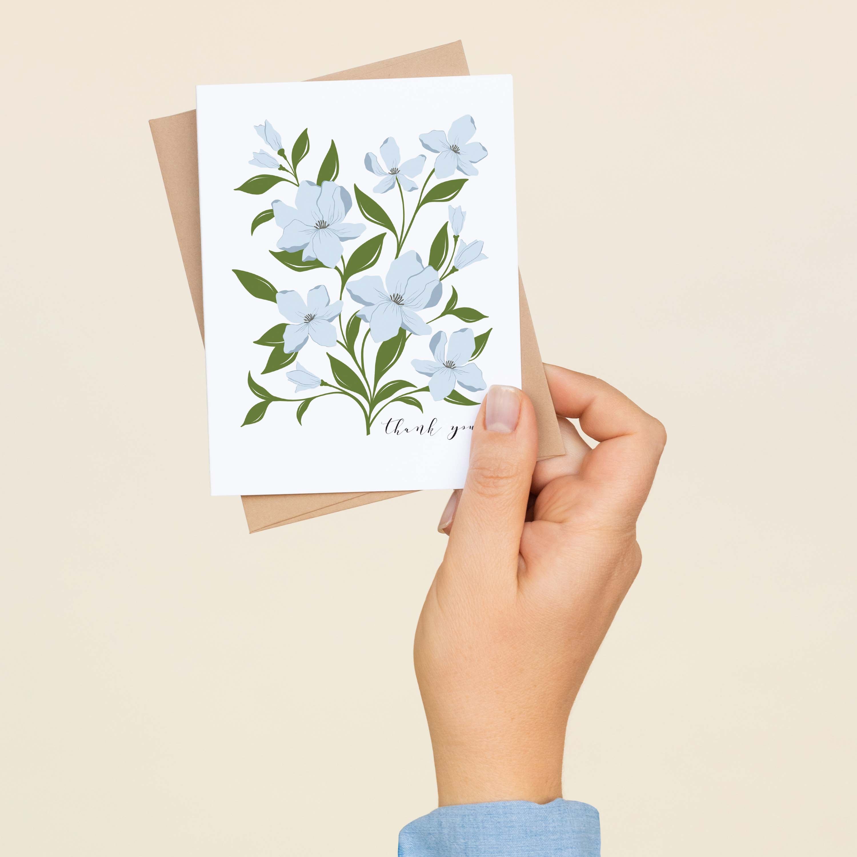 A hand holding a Dogwood Bouquet Thank You greeting card and envelope showing the hand-illustrated dogwood flower design