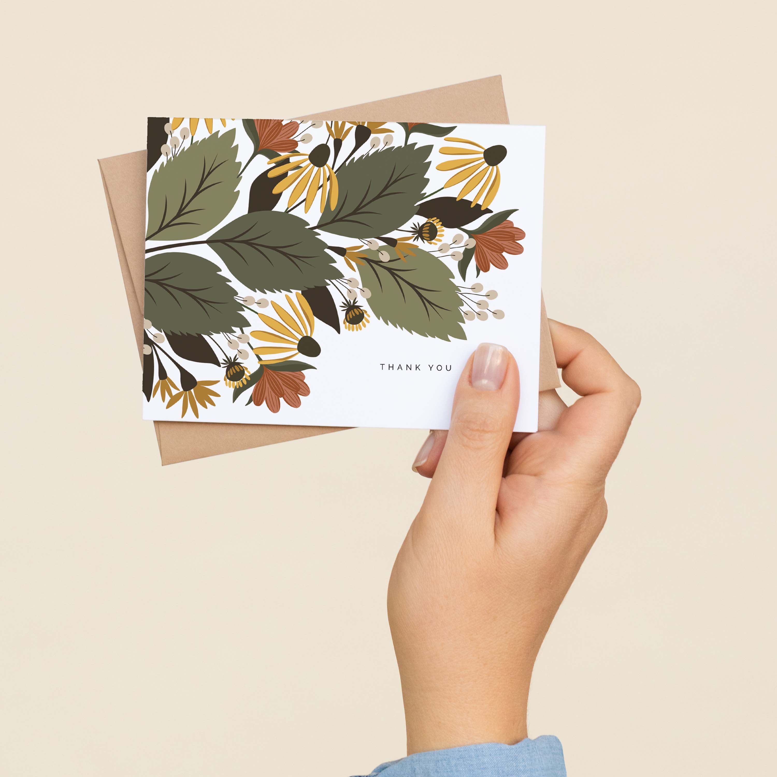 A hand holding a Fall Florals Thank You greeting card and envelope showing the hand-illustrated autumn floral design