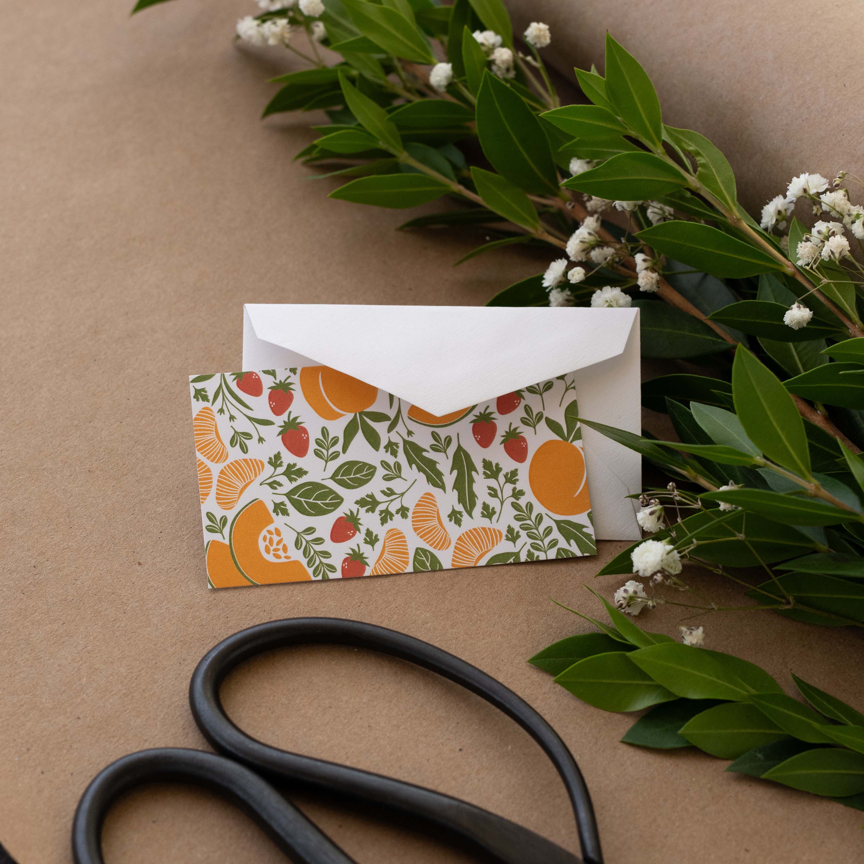 Farmstand Fruits Mini Note Card styled with a white envelope, greenery, and scissors on kraft paper
