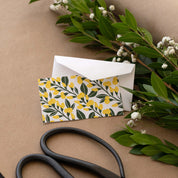 Sundrops Mini Note Card styled with a white envelope, greenery, and scissors on kraft paper