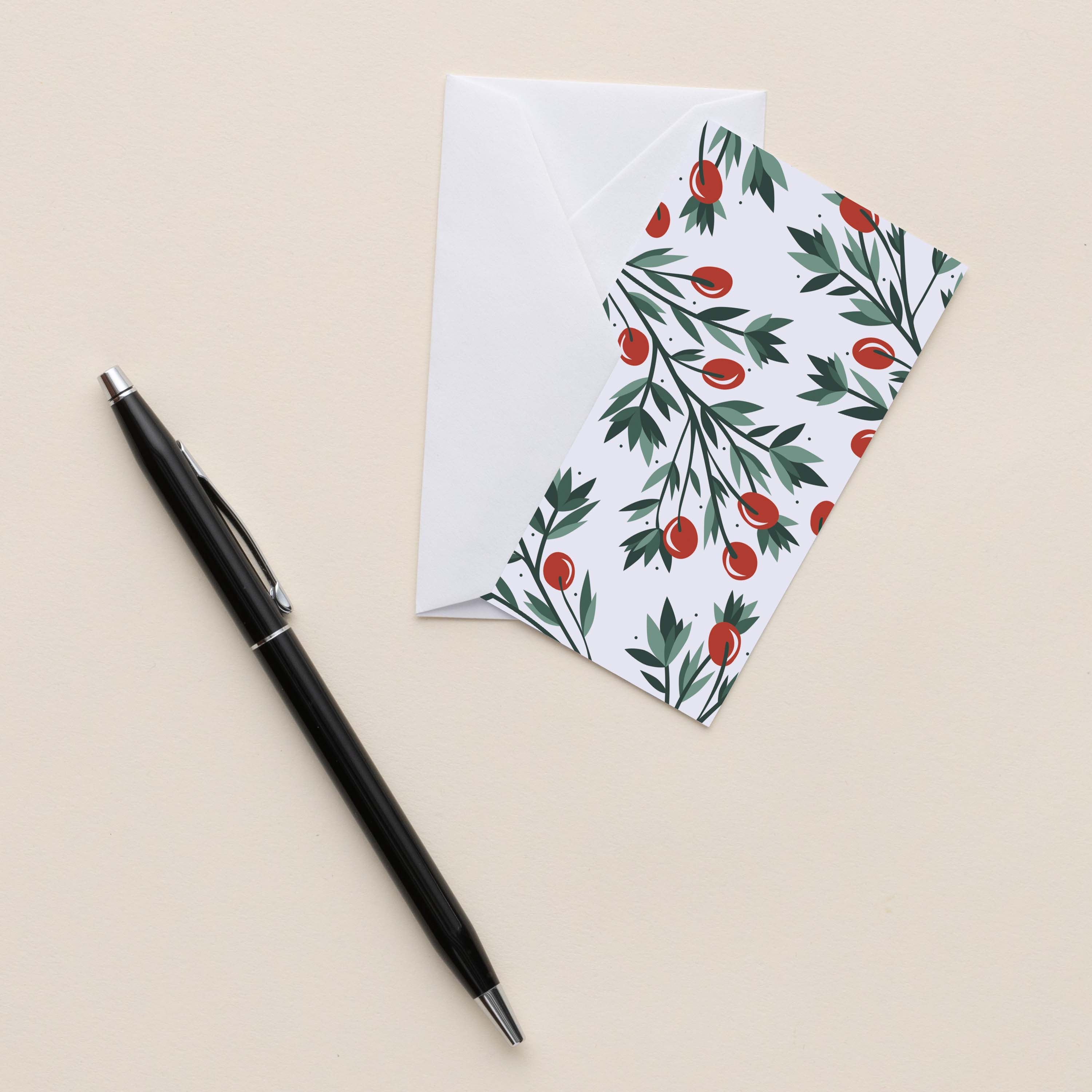 Holly Mini Note Card with white envelope beside a black pen on a neutral background