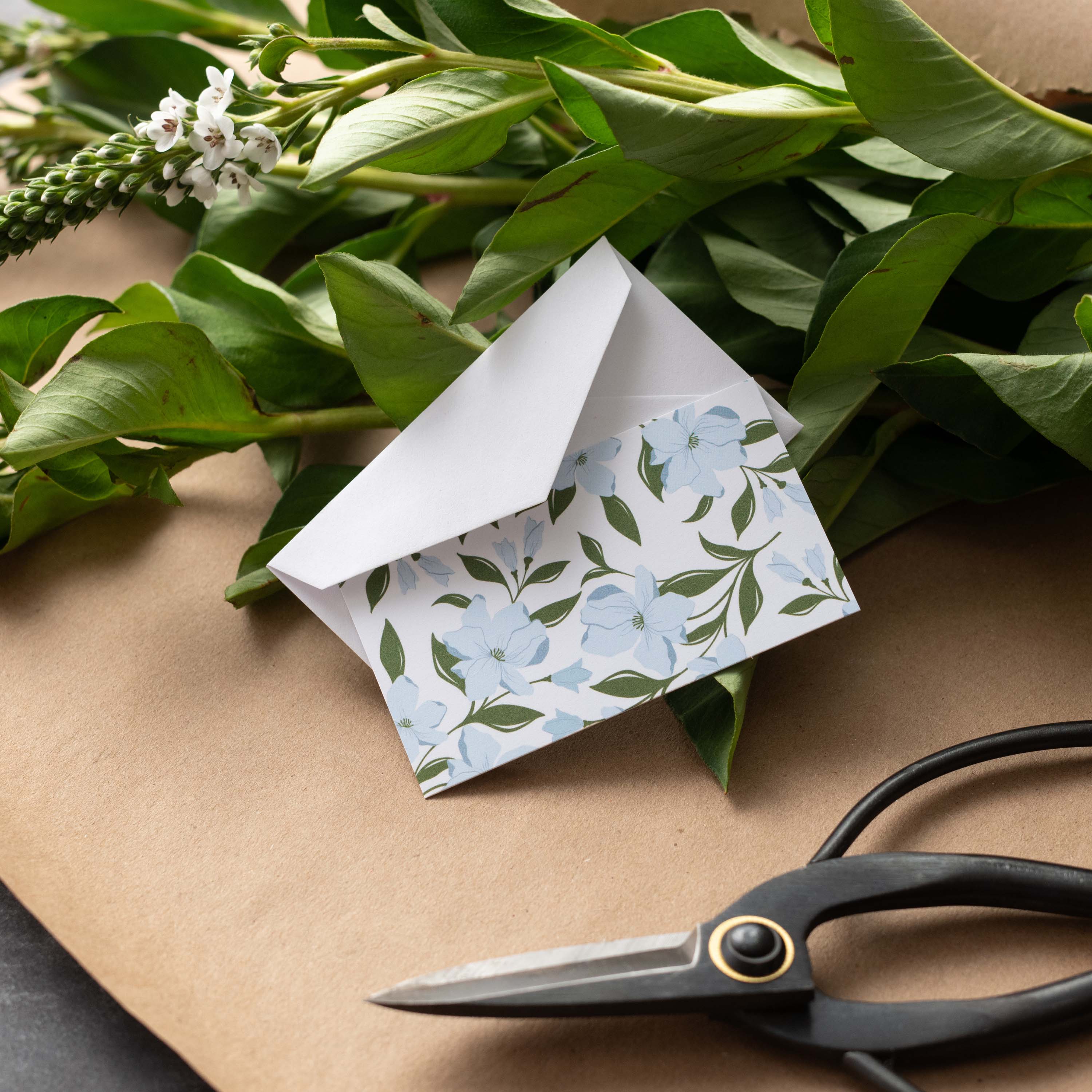 Dogwood Flowers Mini Note Card styled with a white envelope, greenery, and scissors on kraft paper
