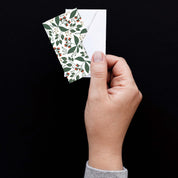 Hand holding a Winterberry Mini Note Card with a white envelope against a dark background