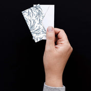Hand holding a Winter Branch Mini Note Card with a white envelope against a dark background