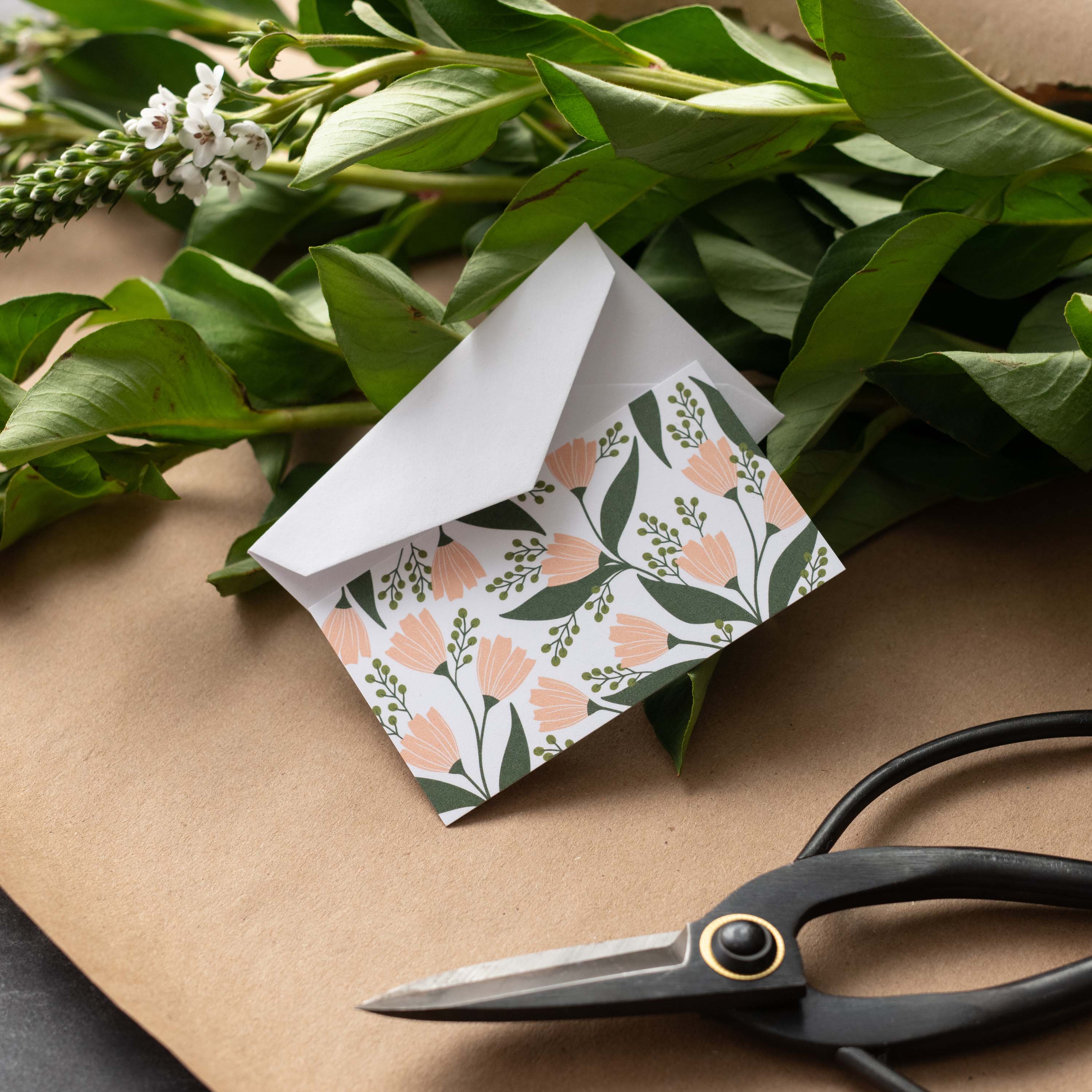 Tea Tin Bouquet Mini Note Card styled with a white envelope, greenery, and scissors on kraft paper