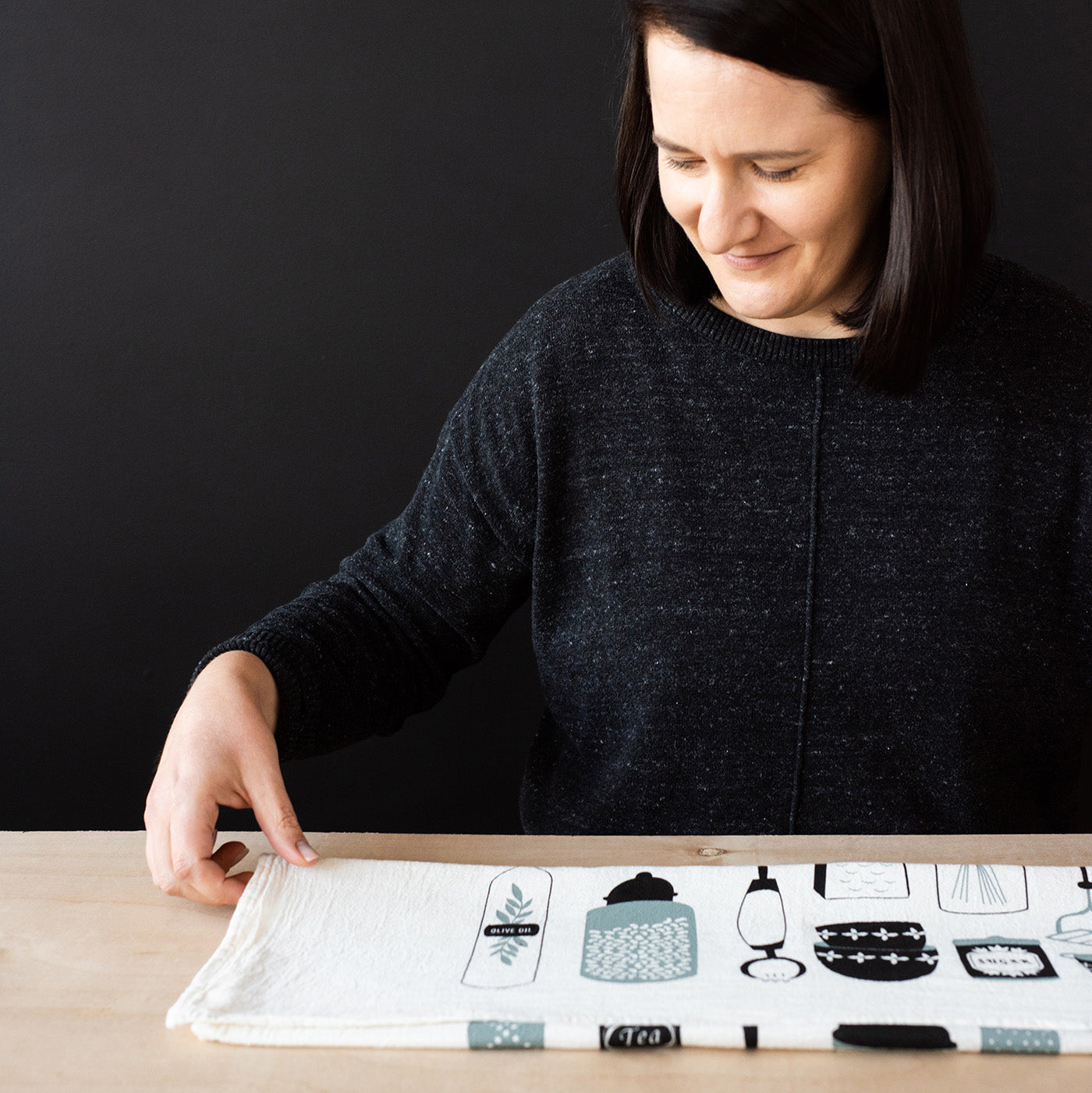 Susan Hazel Rich arranging a Hazelmade tea towel on a tabletop
