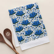 Blue Gentian Tea Towel with hand-illustrated blue floral design beside wooden kitchen utensils