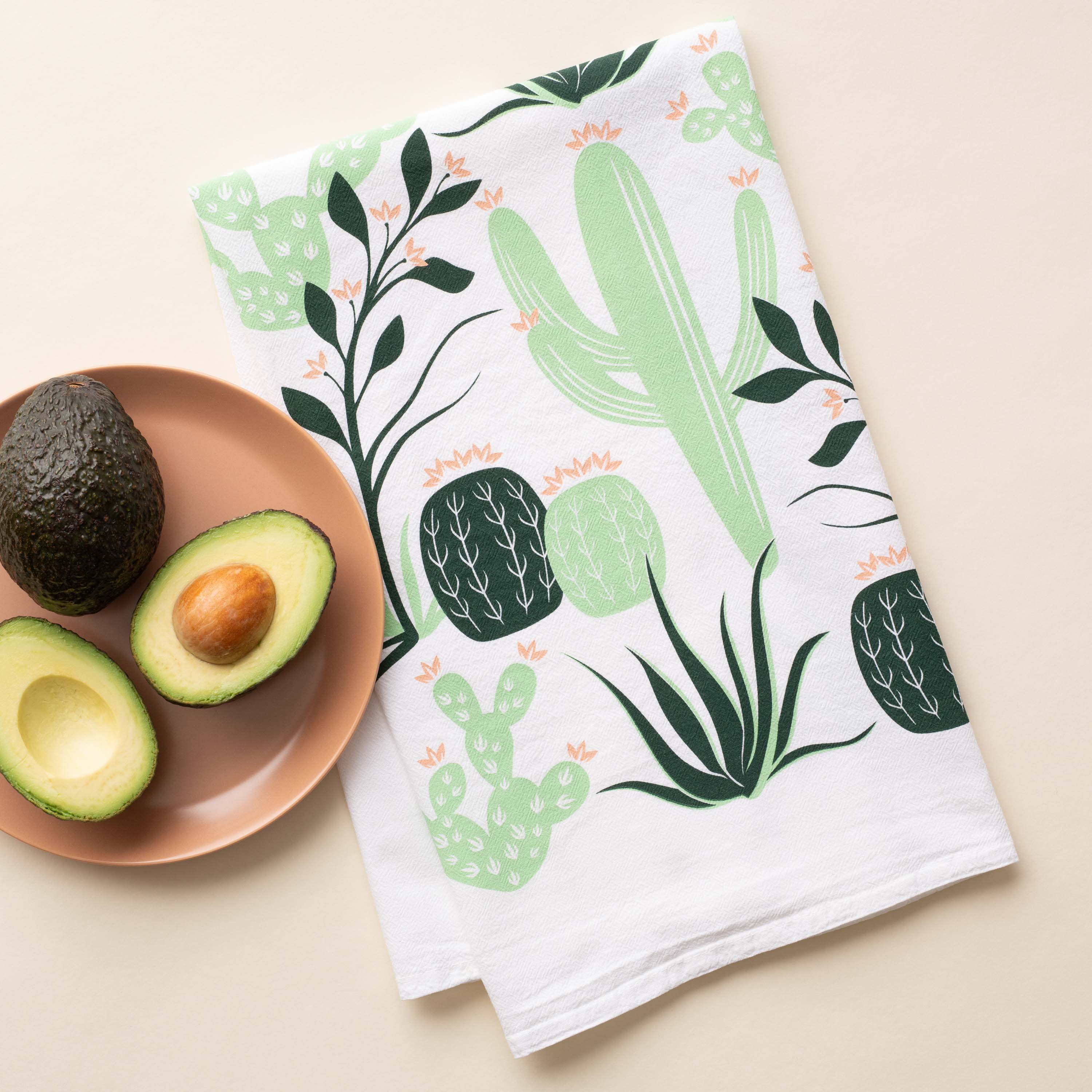 Cactus Tea Towel with hand-illustrated cactus design beside avocados on a plate