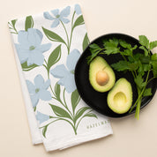 Dogwood Tea Towel with hand-illustrated dogwood flower design beside halved avocados and parsley