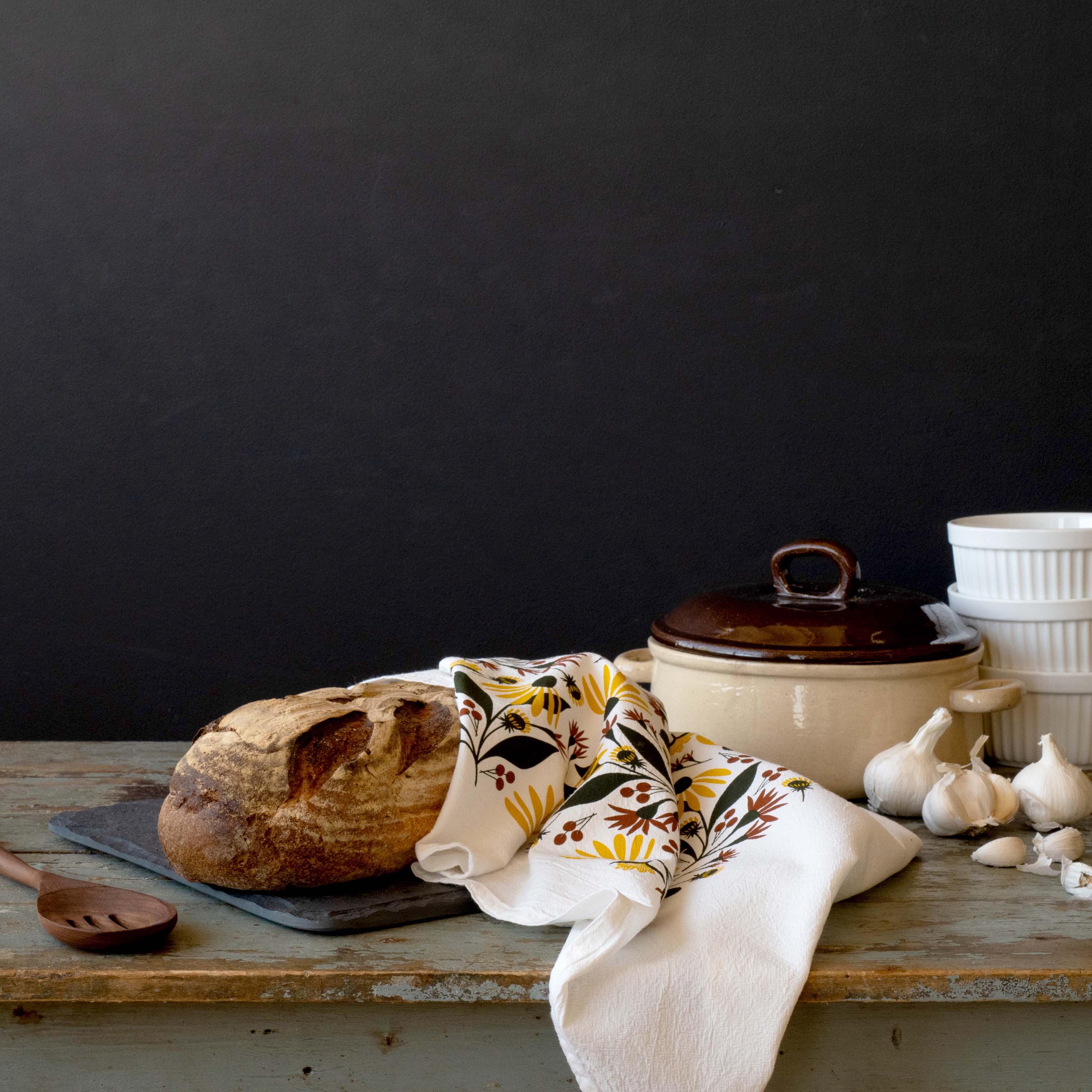 Fall Florals Tea Towel draped over a table beside bread, garlic, and a Dutch oven