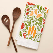 Orange Farmers Market Tea Towel with hand-illustrated vegetable and citrus design beside wooden kitchen utensils