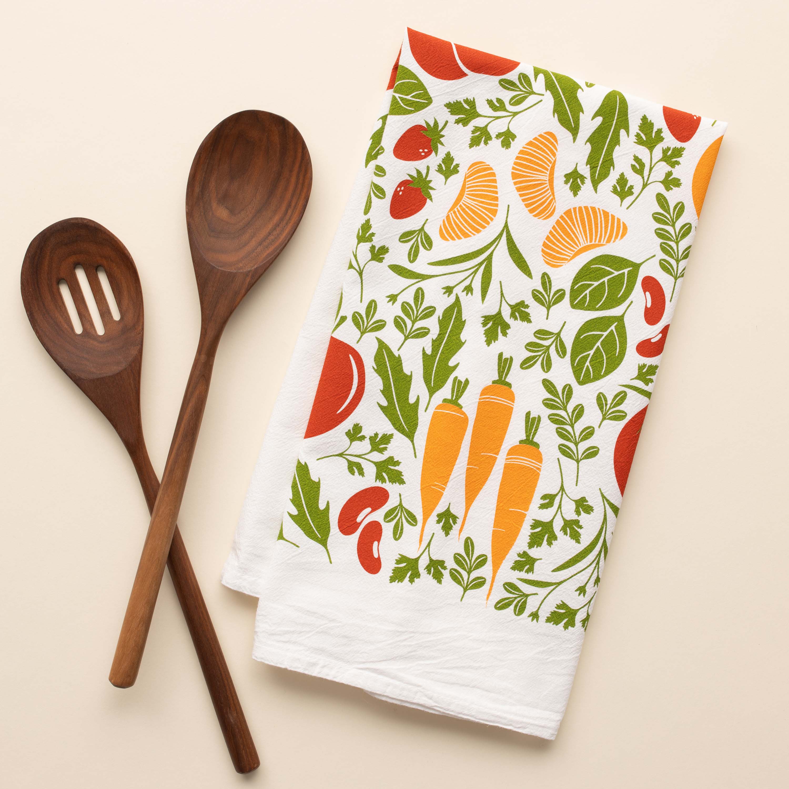 Orange Farmers Market Tea Towel with hand-illustrated vegetable and citrus design beside wooden kitchen utensils