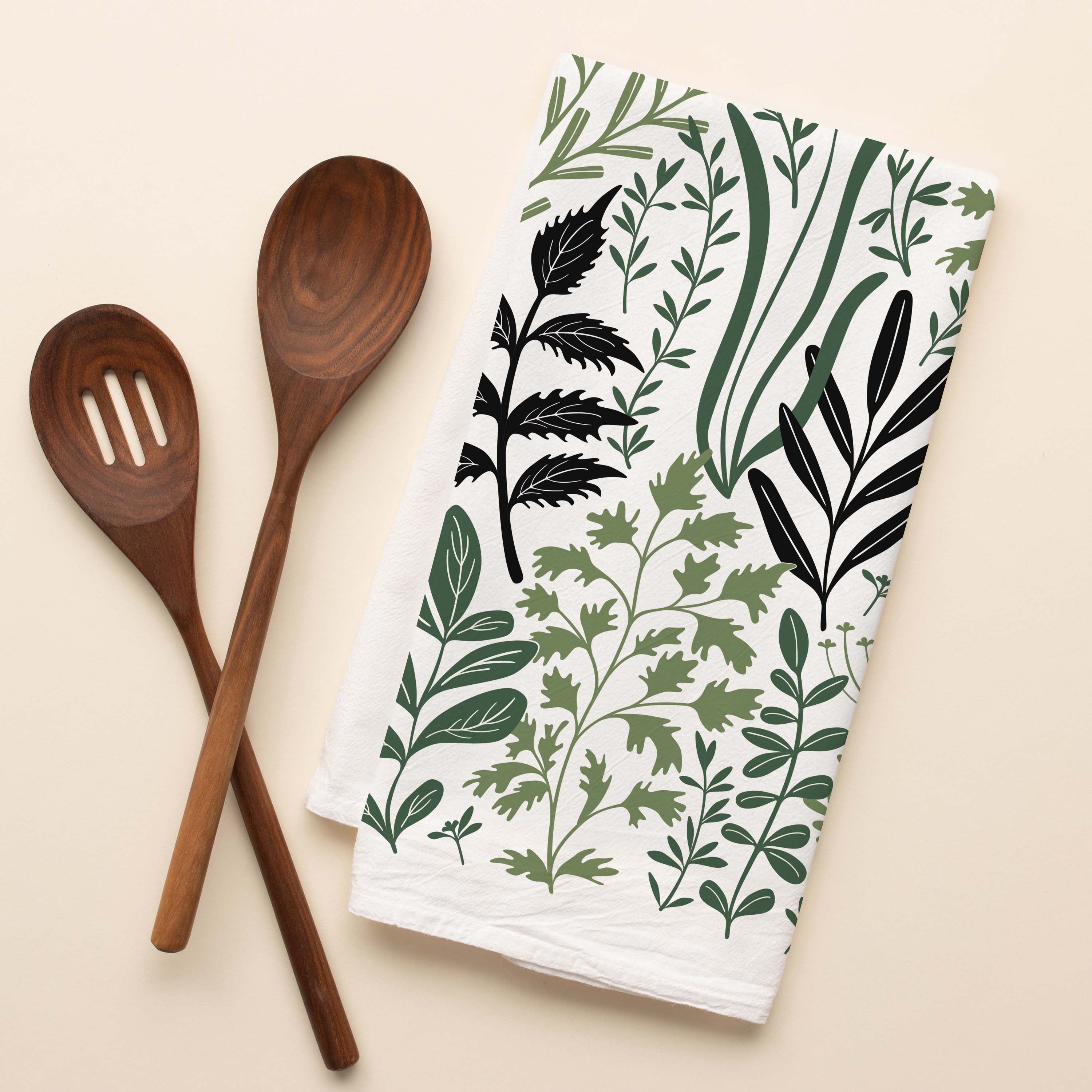 Fresh Herbs Tea Towel with hand-illustrated herb pattern beside wooden kitchen utensils