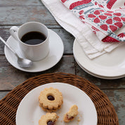 Jam Jars Tea Towel styled beside a coffee cup, plates, and cookies on a wooden table