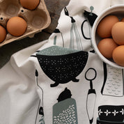 Kitchen Utensils Tea Towel styled beside brown eggs on a wooden table