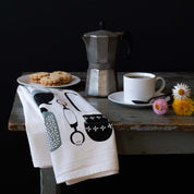 Kitchen Utensils Tea Towel styled with coffee, pastries, and small flowers on a rustic table