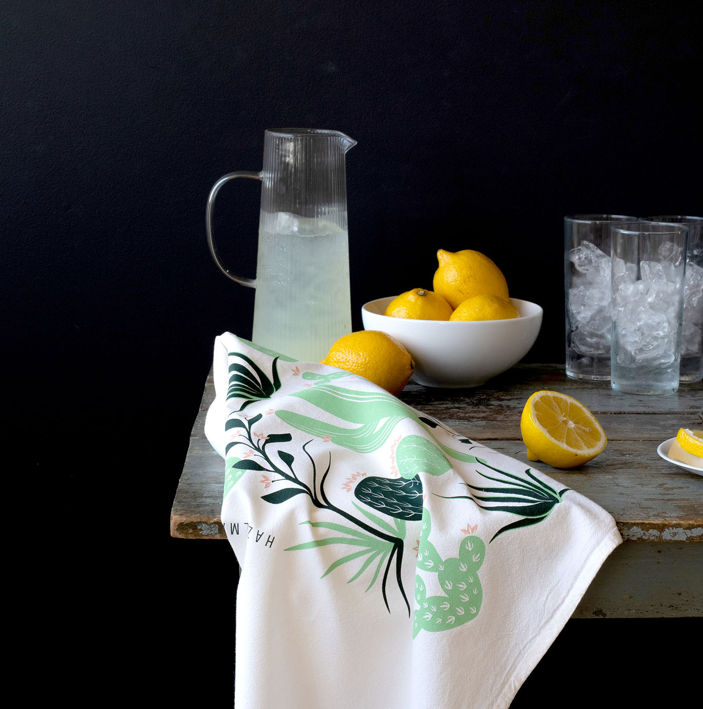 Hazelmade cactus-patterned tea towel styled with lemons, lemonade, and glasses on a rustic table