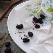 Pickles + Petals Tea Towel styled with blackberries on a white plate next to a wooden spoon