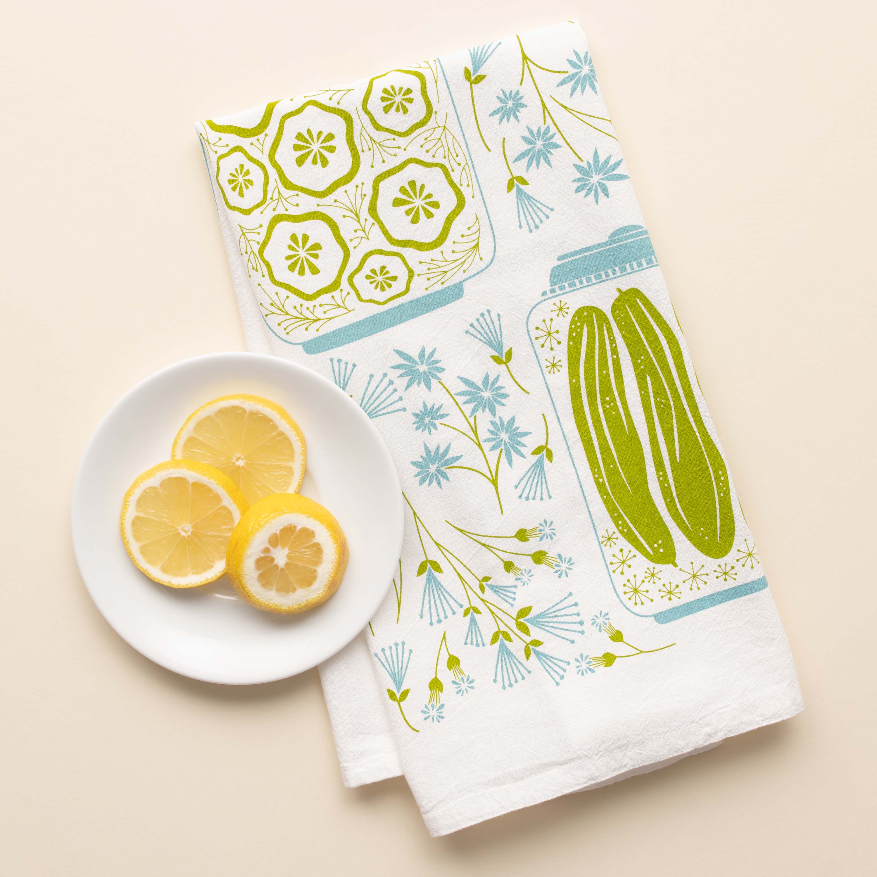 Pickles + Petals Tea Towel with hand-illustrated pickle jar and floral design beside sliced lemons