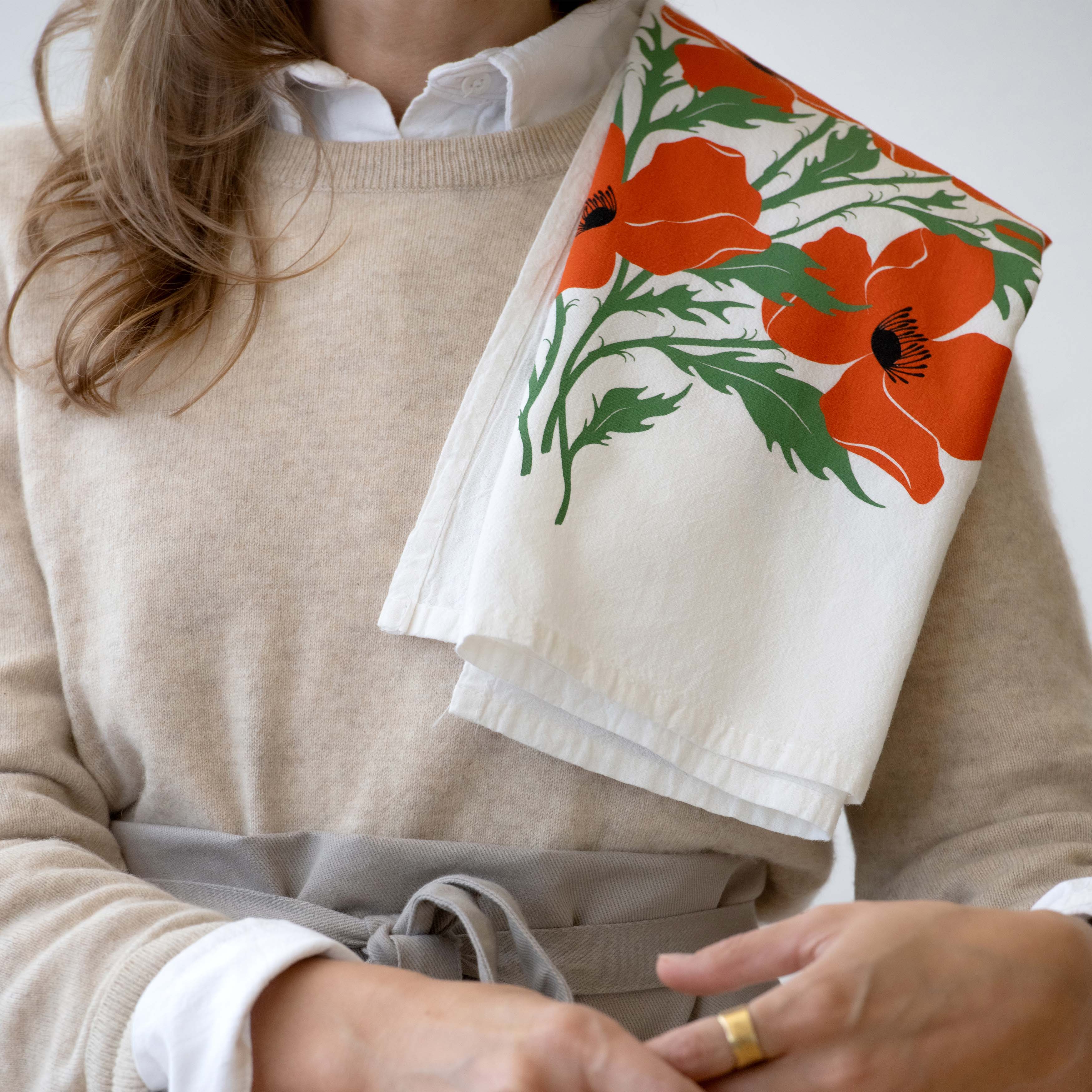 Person holding the Poppies Tea Towel over their shoulder