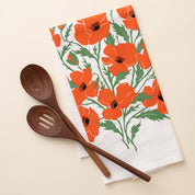 Poppies Tea Towel with hand-illustrated poppy design beside wooden kitchen utensils