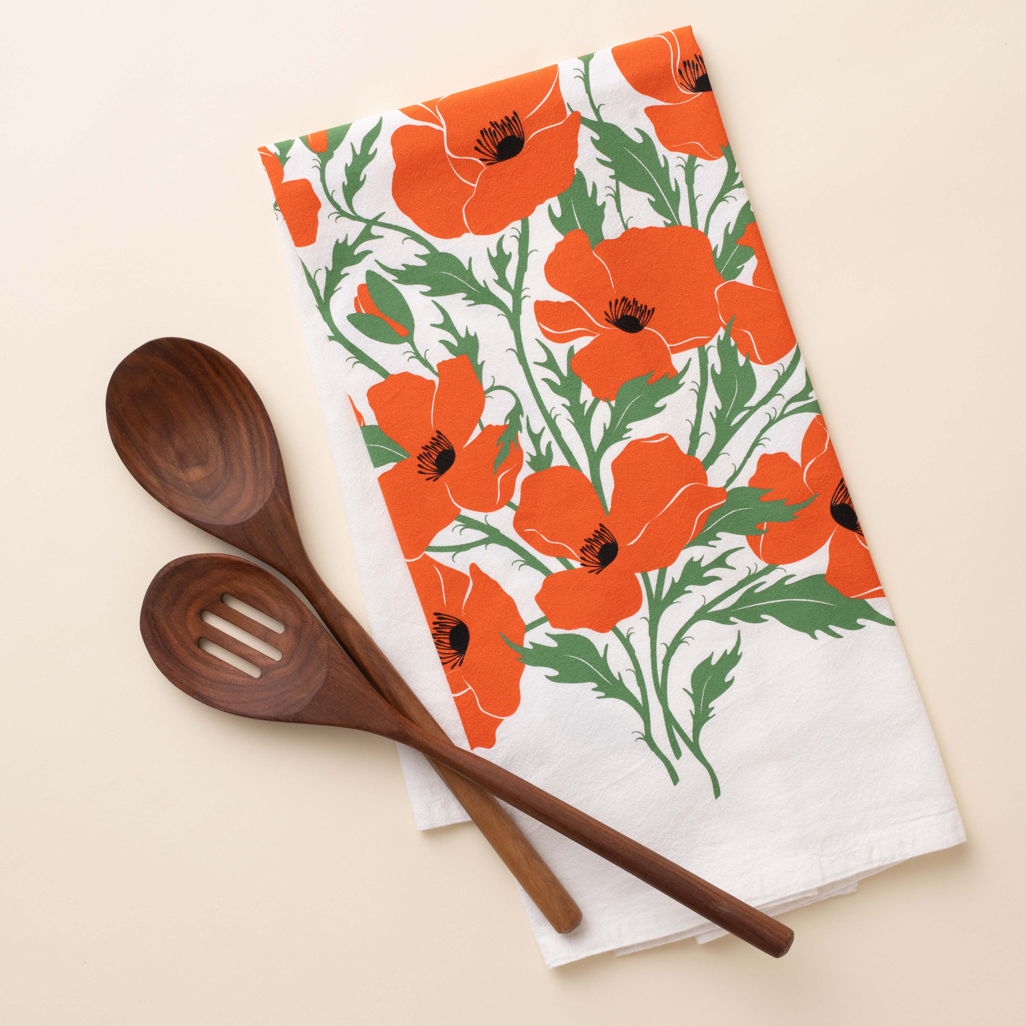 Poppies Tea Towel with hand-illustrated poppy design beside wooden kitchen utensils