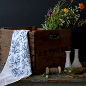 Winter Branch Tea Towel styled with a wooden crate, wildflowers, and glass vases