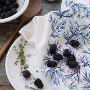 Winter Branch Tea Towel styled with blackberries and herbs on a wooden tabletop
