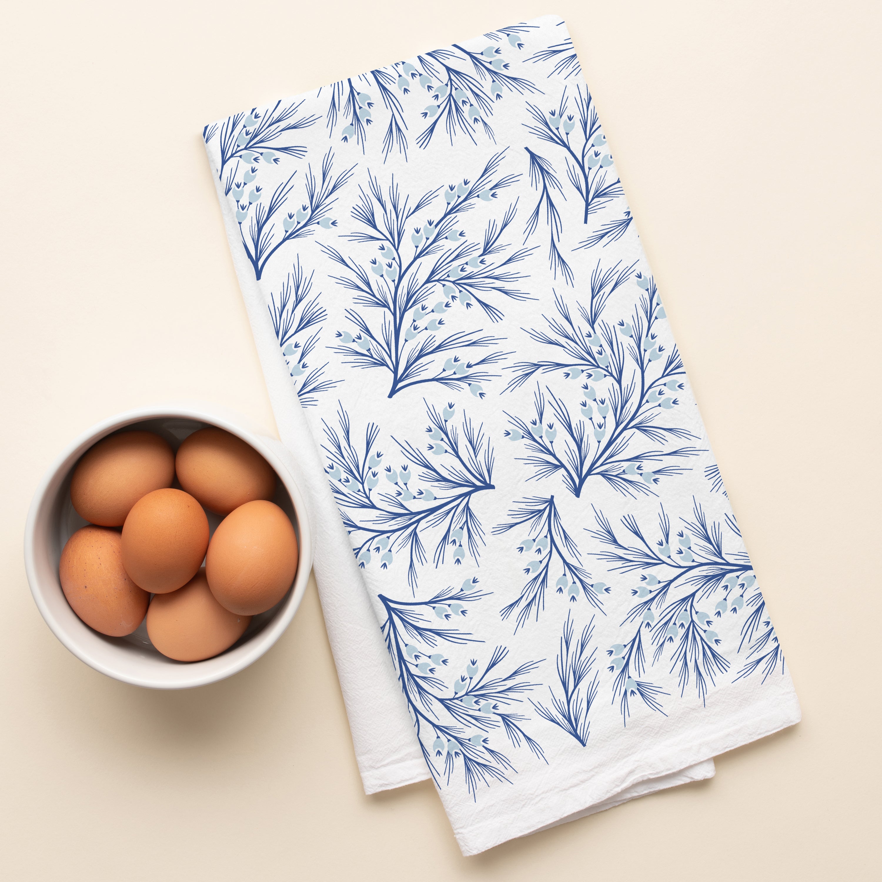 Winter Branch Tea Towel with hand-illustrated winter branch design beside a bowl of brown eggs