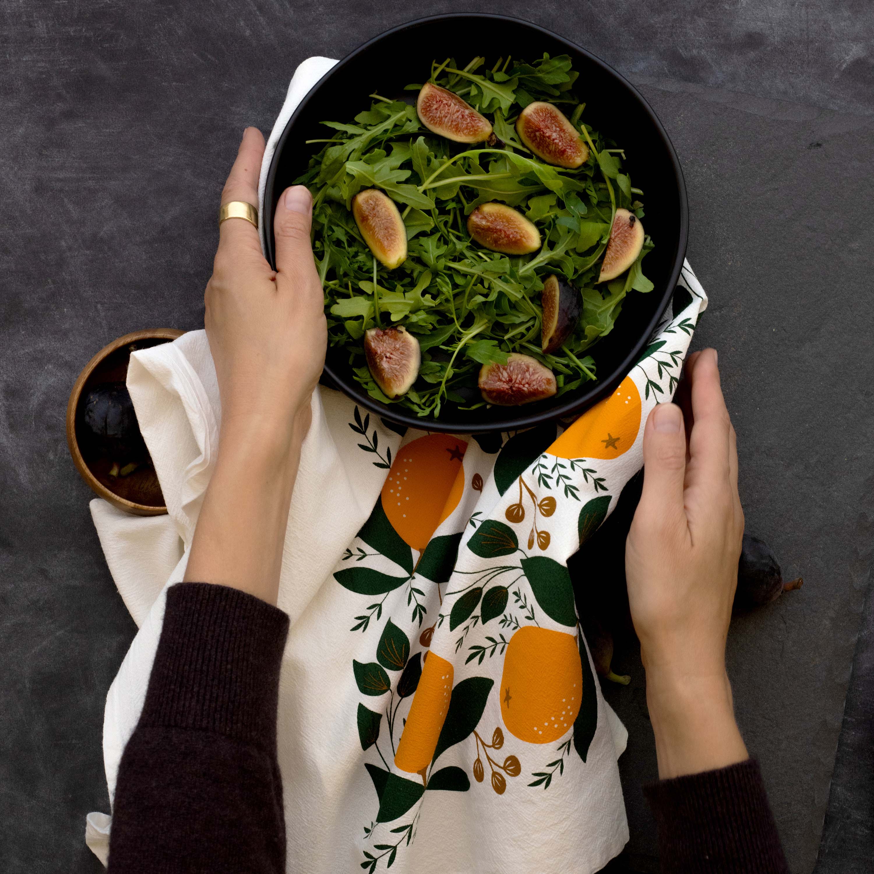 Winter Citrus Tea Towel styled beneath a bowl of fig salad held by two hands