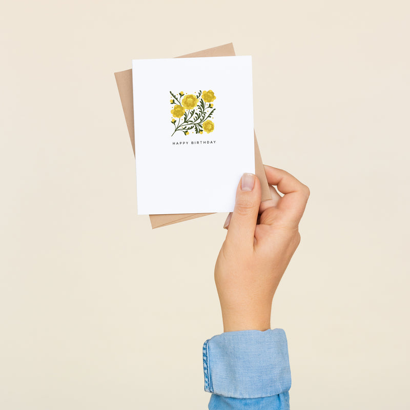 Box set of 8 folded A2 greeting cards with envelopes with an illustration of marigolds. Under the illustration, the text states "Happy Birthday".