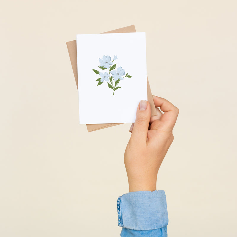 Single folded A2 greeting card with an envelope with an illustration of blue dogwood flowers in the center of the card.