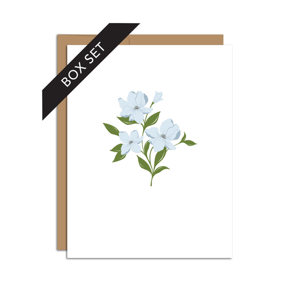 Box set of 8 folded A2 greeting cards with envelopes with an illustration of blue dogwood flowers in the center of the card.