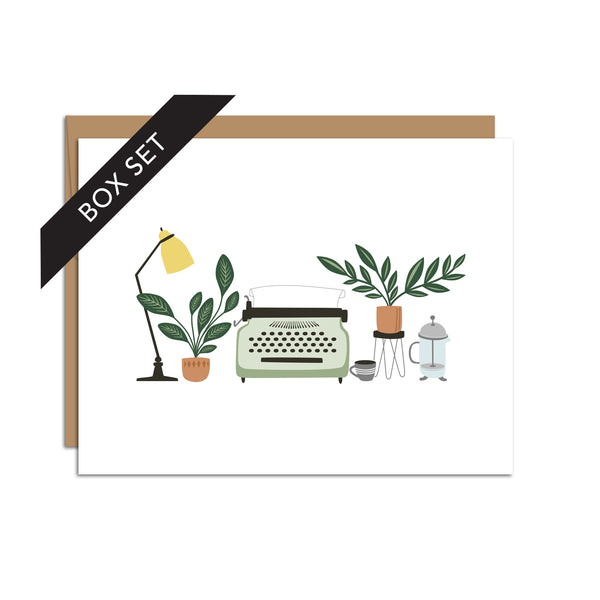 Box set of 8 folded A2 greeting cards with envelopes with an illustration of a lamp, plant, typewriter, and various other desk items in the center of the card.