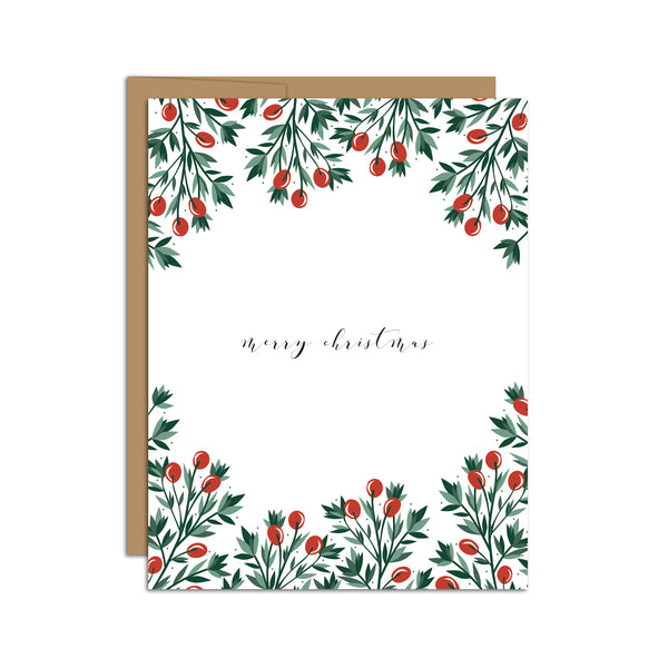 Single folded A2 greeting card with an envelope with an illustration of red holly berries and green leaves bordering the top and bottom of the card. In the center of the card is text in cursive that states "Merry Christmas".